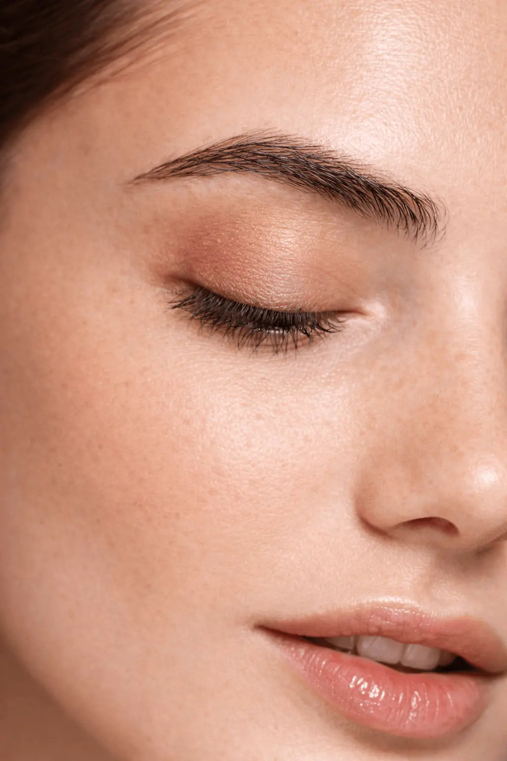 Close-up of a woman's face with closed eyes and pink lipstick.