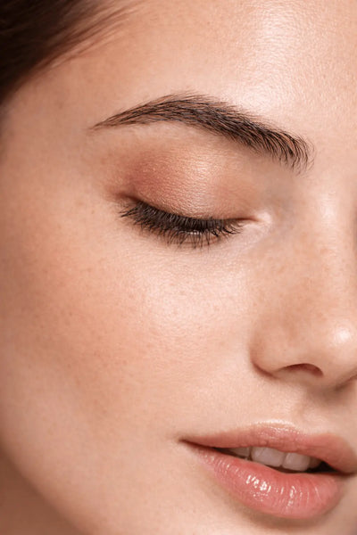 Close-up of a woman's face with closed eyes and pink lipstick.