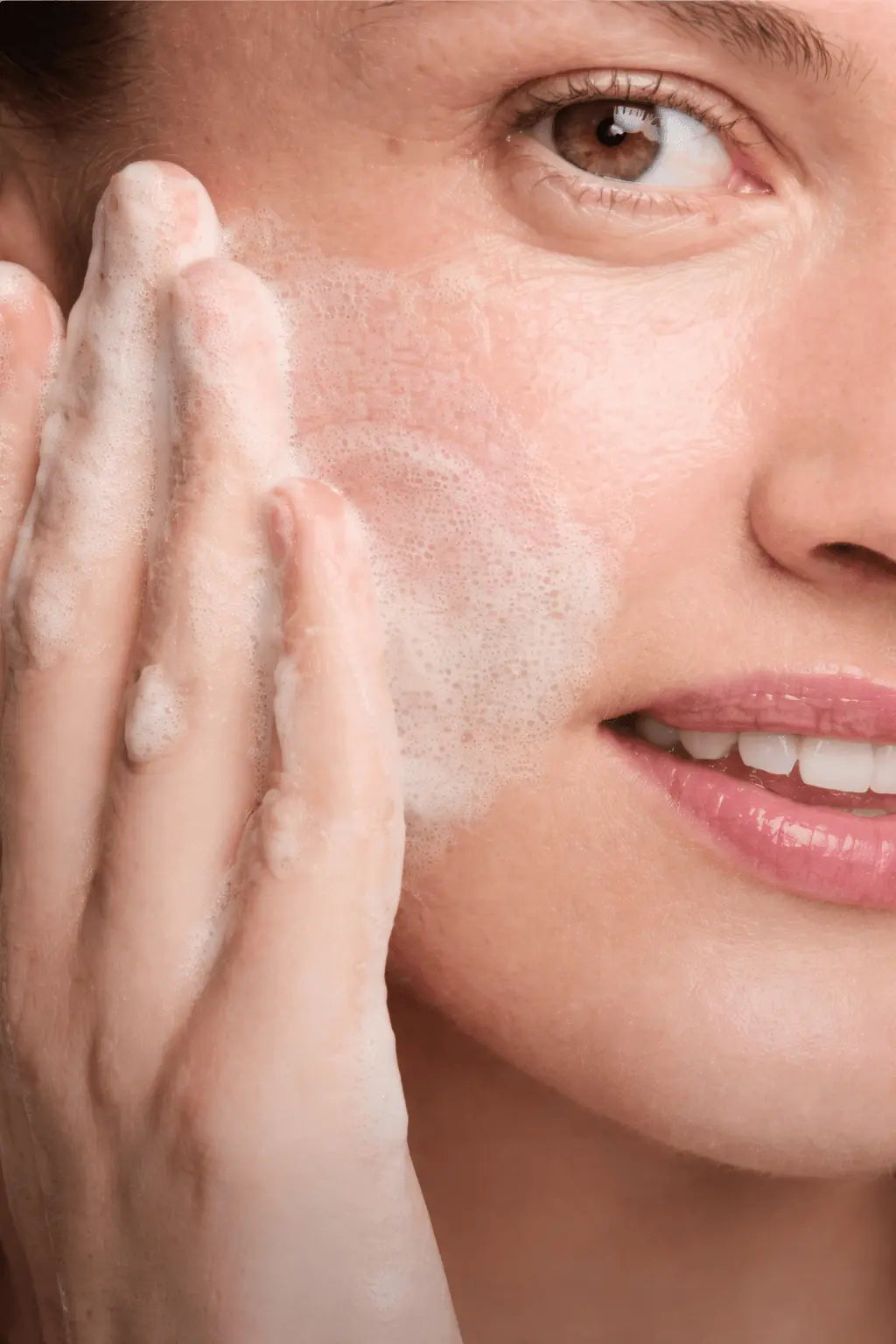 Close-up of a woman applying a skincare product to her face.