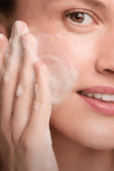 Close-up of a woman applying a skincare product to her face.