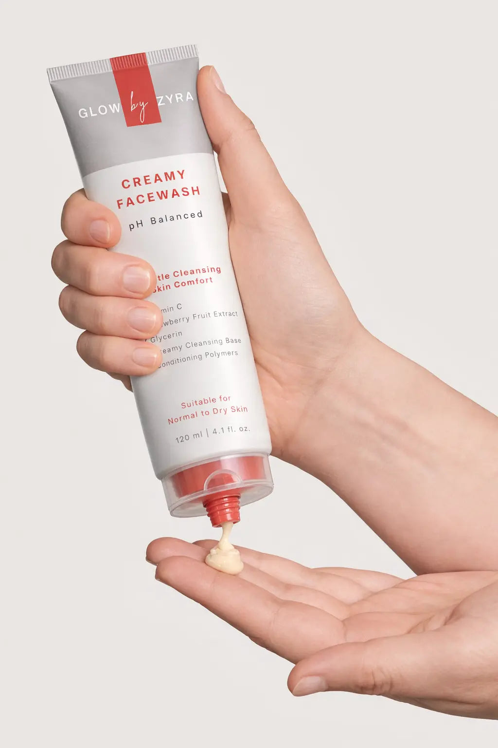 Hand holding a tube of Glow by Zya Creamy Facewash with a small amount on the palm.