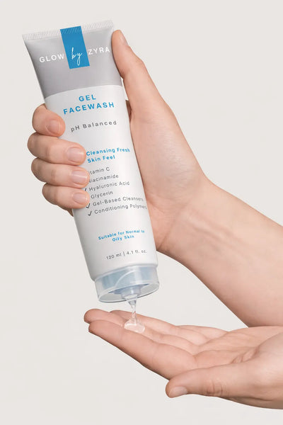 Hand holding a tube of 'Glow by Zyra' gel face wash with a small amount on the palm.